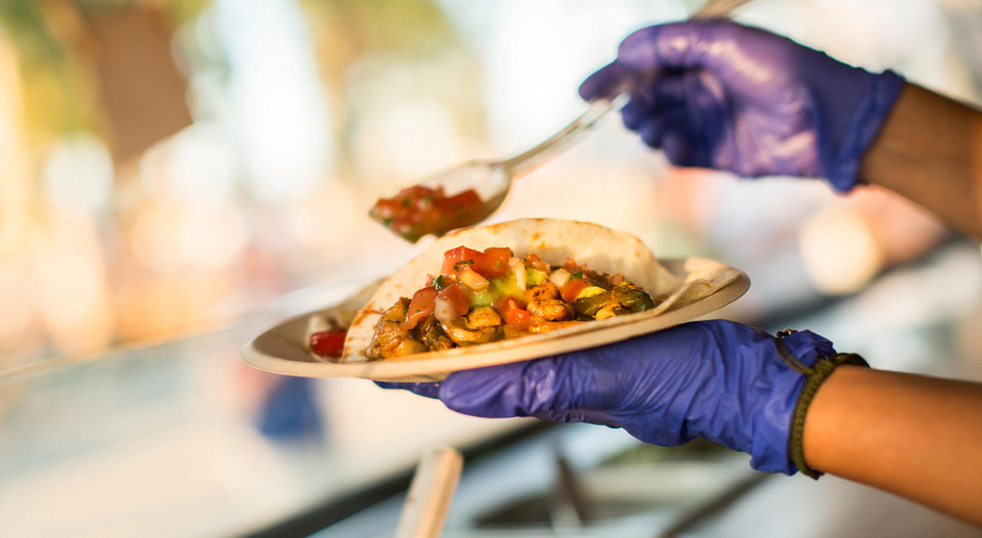 chef wearing gloves preparing tacos in a food truck