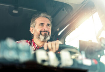 front view of truck driver sitting in his mack semi truck and driving to a warehouse