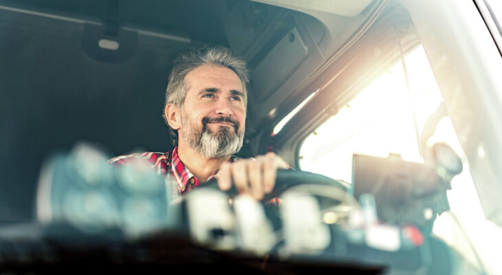 front view of truck driver sitting in his mack semi truck and driving to a warehouse