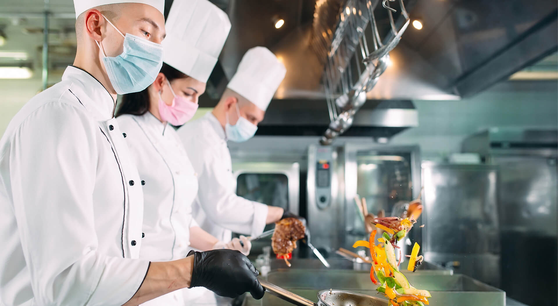 chefs in protective masks and gloves prepare food in a ghost kitchen