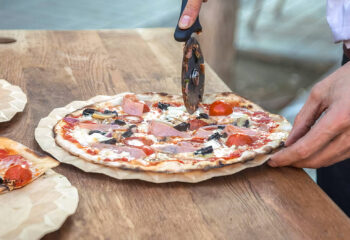 pizza food truck server cuts slices of pizza on the counter of a food truck