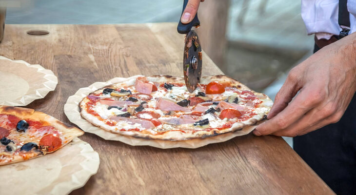 pizza food truck server cuts slices of pizza on the counter of a food truck