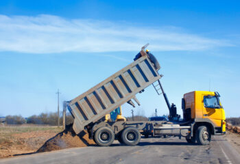 dump truck dumps sand on the side of the road during roadworks