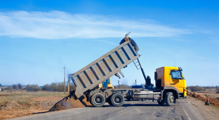 dump truck dumps sand on the side of the road during roadworks