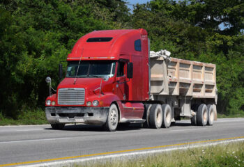 red Freightliner truck driving on the road