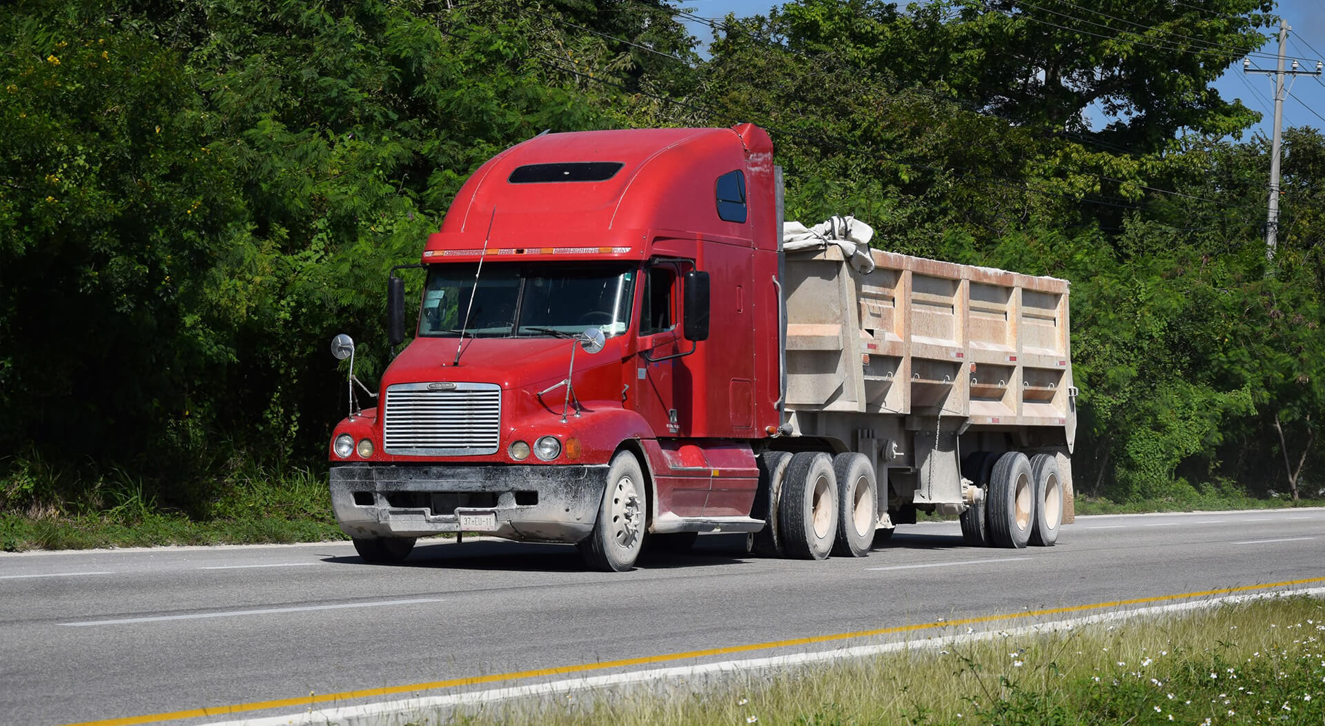 red Freightliner truck driving on the road