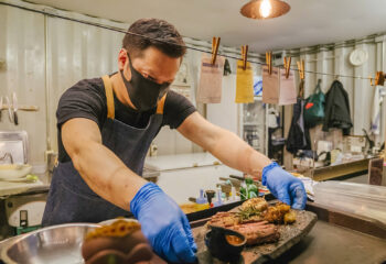 food truck business owner reopening a restaurant after quarantine and preparing food while wearing a face mask and glove