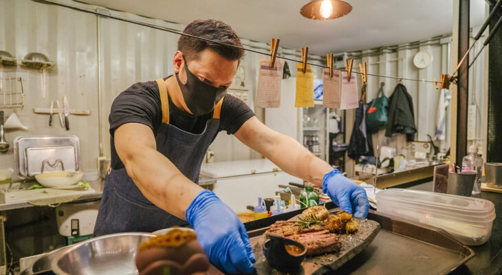 food truck business owner reopening a restaurant after quarantine and preparing food while wearing a face mask and glove
