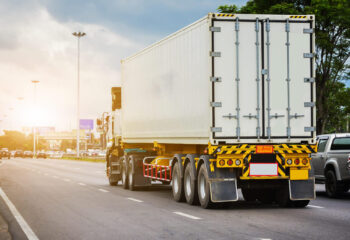 white semi truck driving on a road during summer