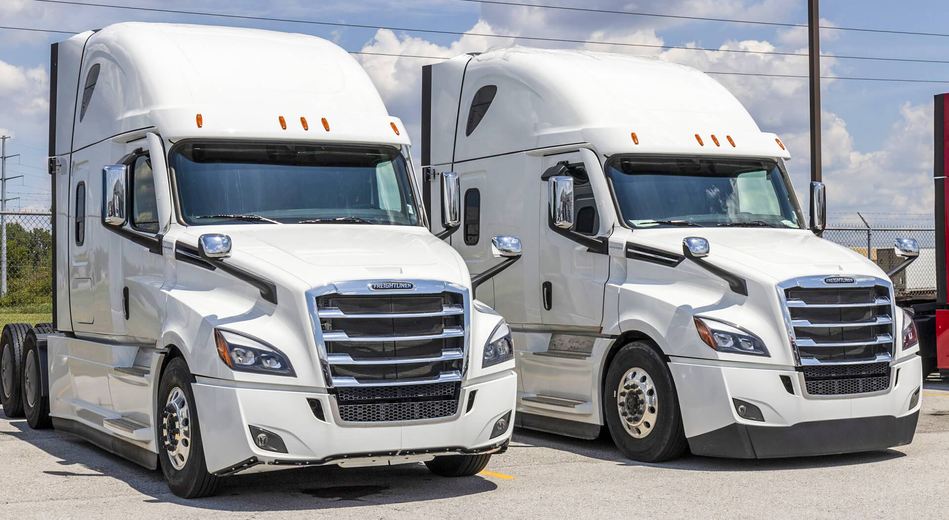 two white Freightliner sleeper trucks lined up for sale