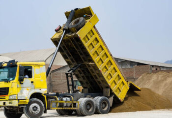 yellow dump truck delivering a load of dirt for a fill project at a new commercial development construction project