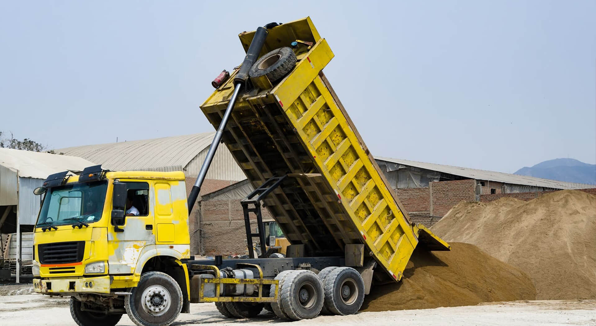 yellow dump truck delivering a load of dirt for a fill project at a new commercial development construction project