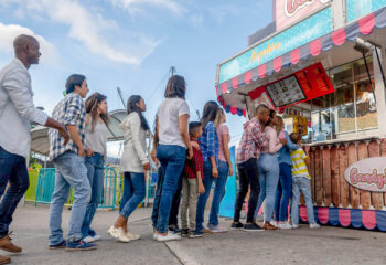 happy people at a funfair lined up to buy food at a candy shop