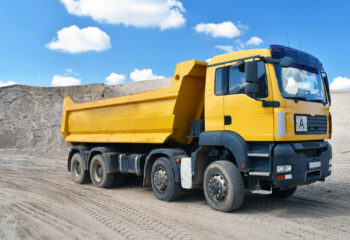 yellow dump truck transports sand in a gravel pit