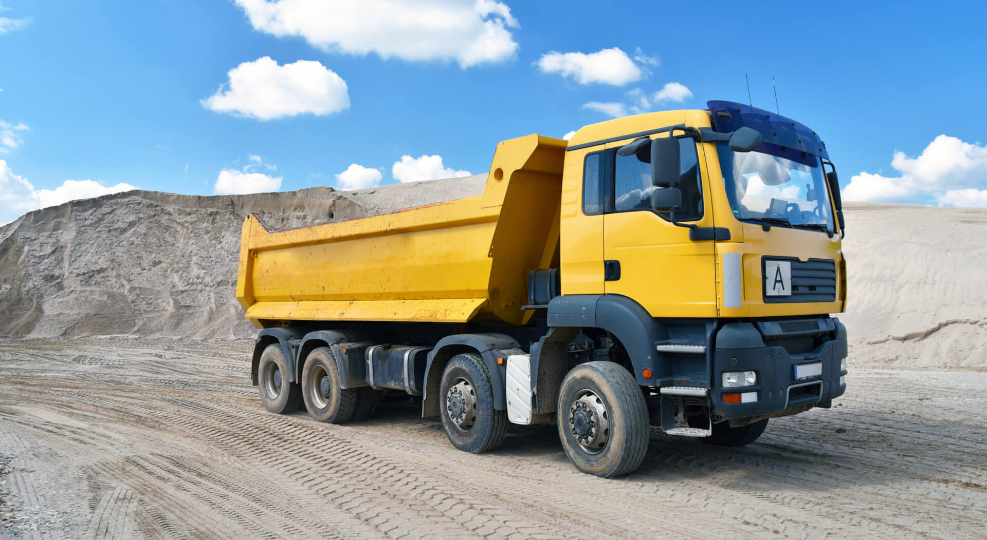 yellow dump truck transports sand in a gravel pit