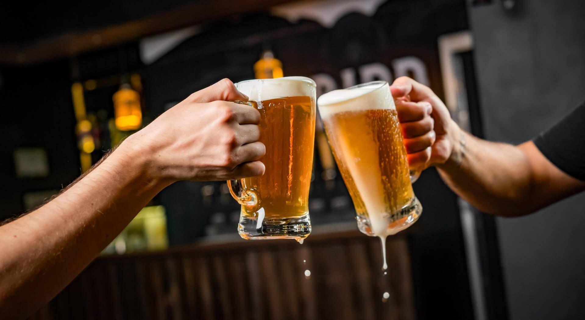 two people in front of a food truck toasting with mugs full of beer