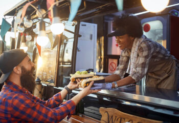 young man taking two sandwiches from polite female food truck employee