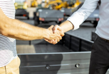 two businessmen shaking hands after sale of used semi truck