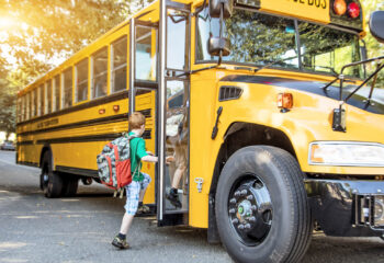 A group of young children getting on the school bus