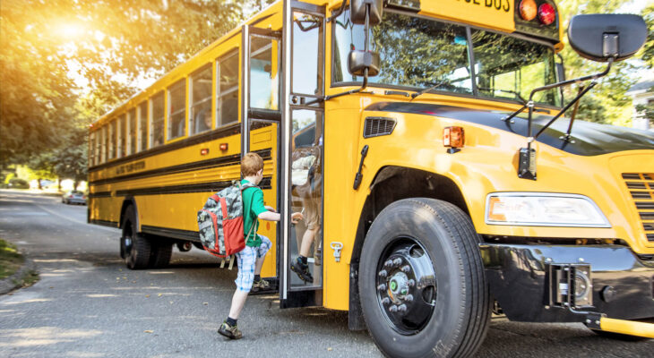 A group of young children getting on the school bus