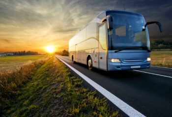 bus traveling on the asphalt road in rural landscape at sunset