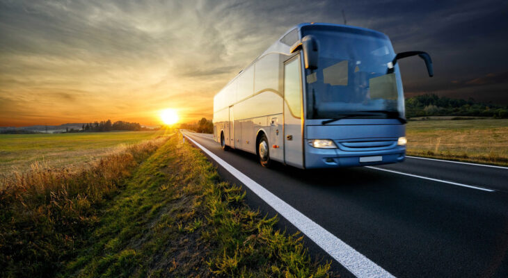 bus traveling on the asphalt road in rural landscape at sunset