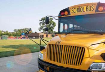 yellow school bus parked in front of school playground