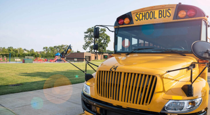 yellow school bus parked in front of school playground