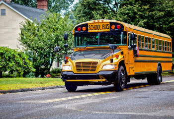 Yellow school bus driving along street