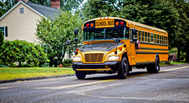 Yellow school bus driving along street