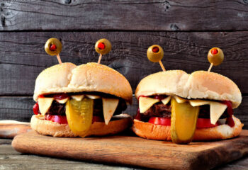 Halloween monster hamburgers on a paddle board against an old wood background