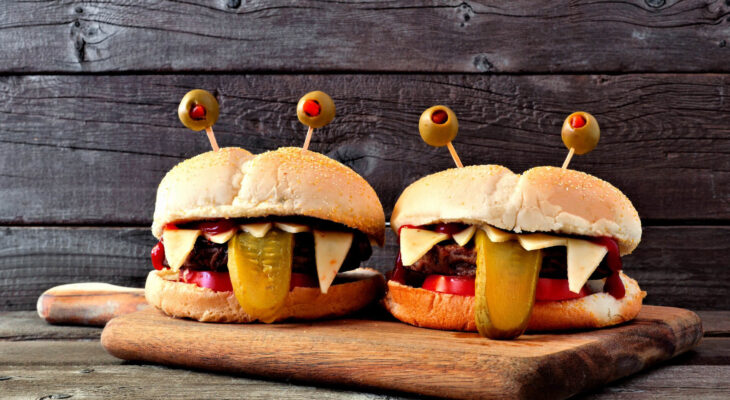 Halloween monster hamburgers on a paddle board against an old wood background