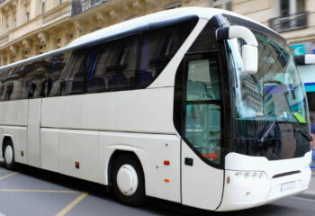 white shuttle bus driving in a street