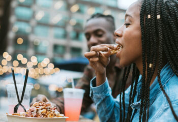 A group of friends having fun in New York city and eating at a large food truck area downtown