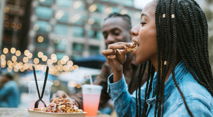 A group of friends having fun in New York city and eating at a large food truck area downtown