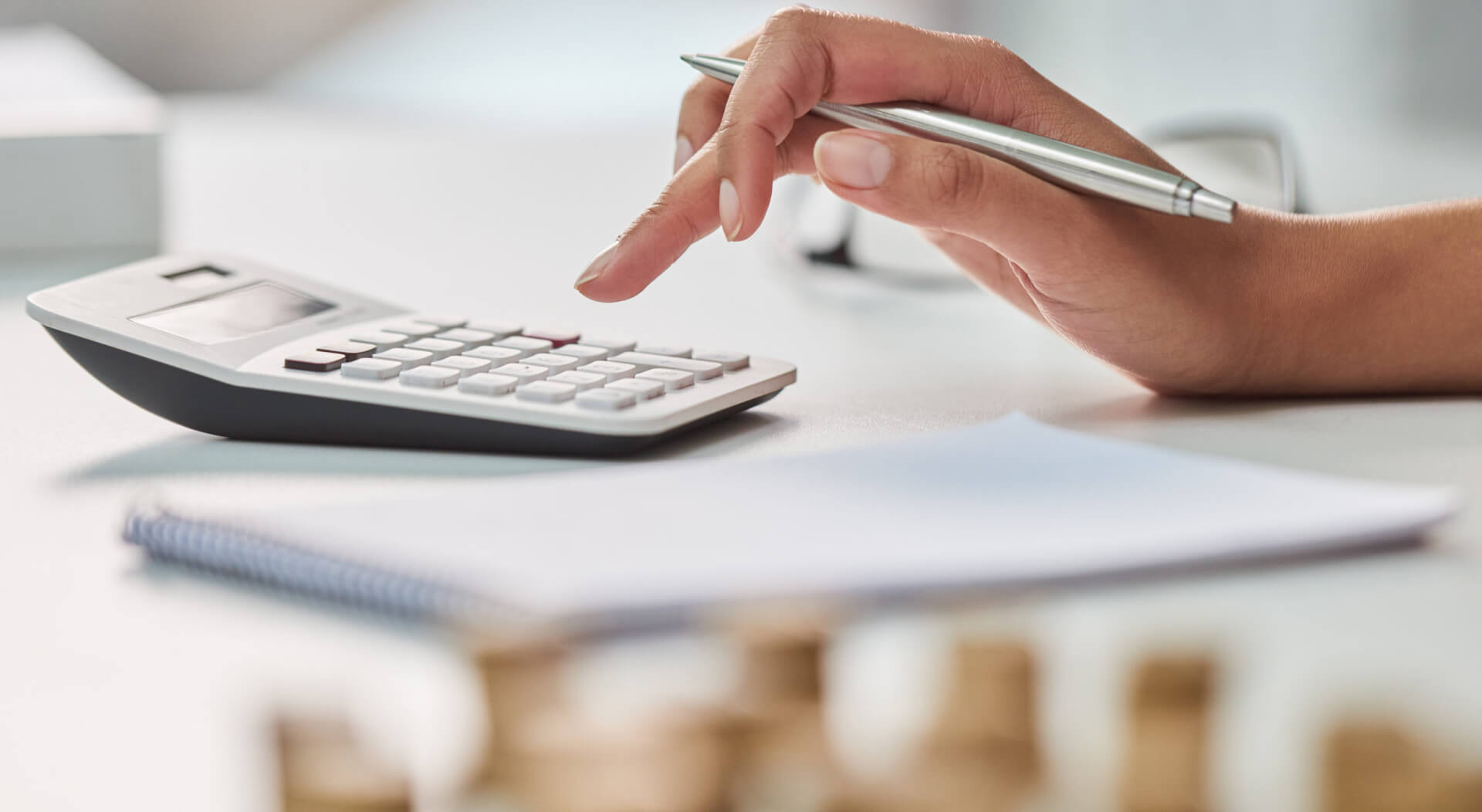 person's hand holding a ballpen while using a calculator