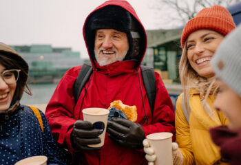 group of friends eating sandwiches and drinking iced tea from a food truck during winter