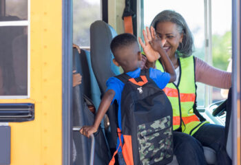 school bus driving picking up a kid