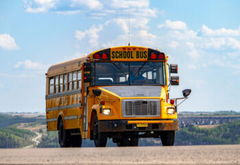 yellow school bus being driven at a road to school