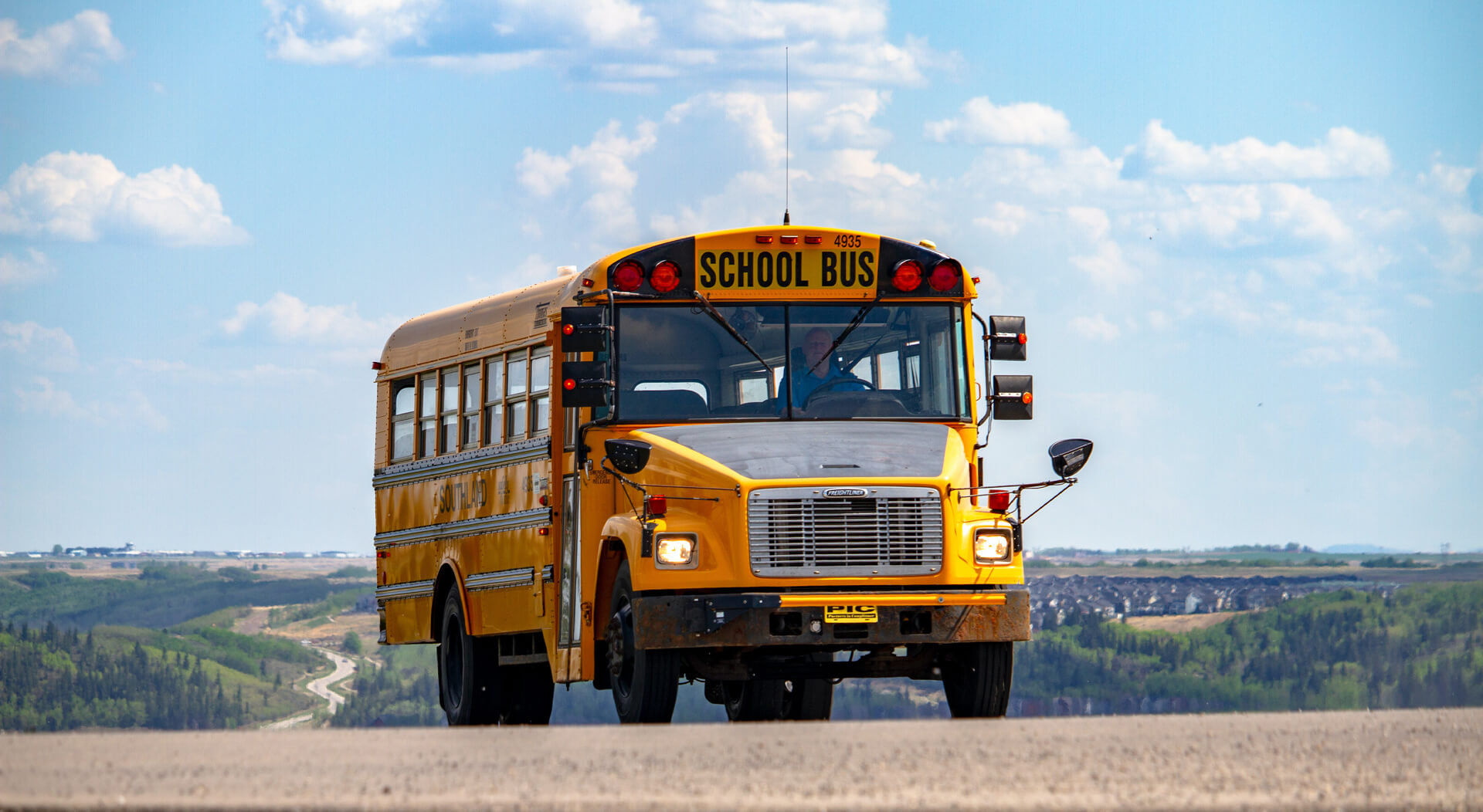 yellow school bus being driven at a road to school