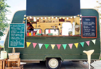 green food truck parked in a sunny park