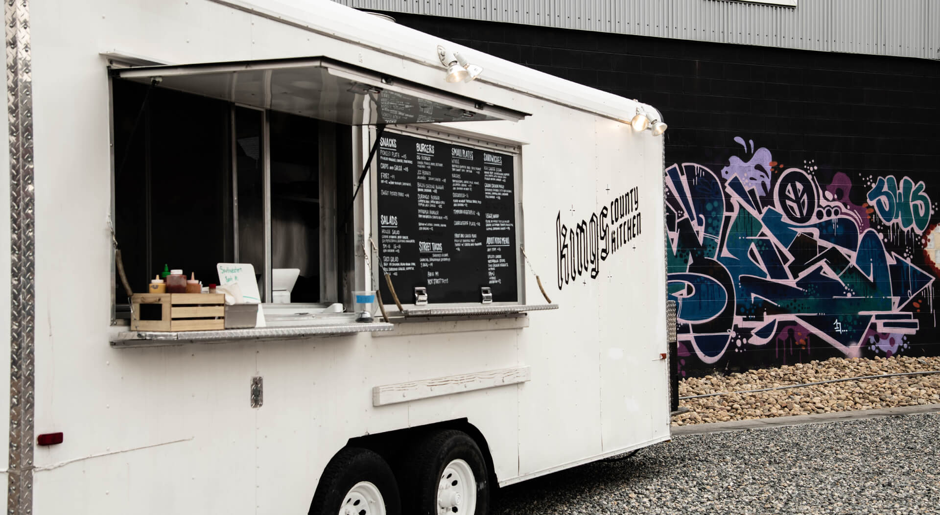 white concession trailer used as a food truck near a graffiti wall