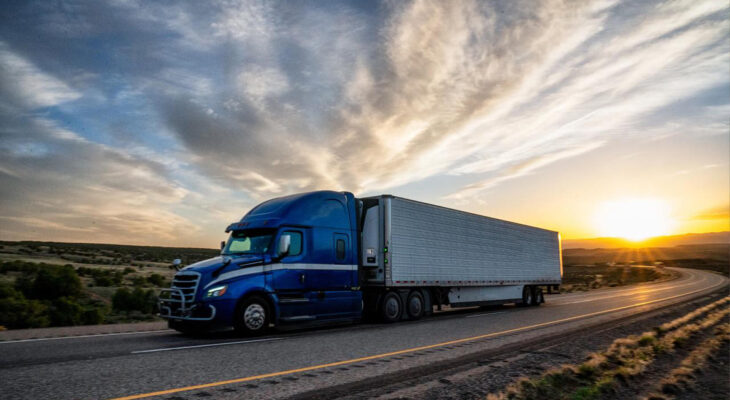 blue 18-wheeler truck on the road during sunset