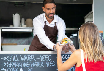 food truck owner serving a cheeseburger to a customer
