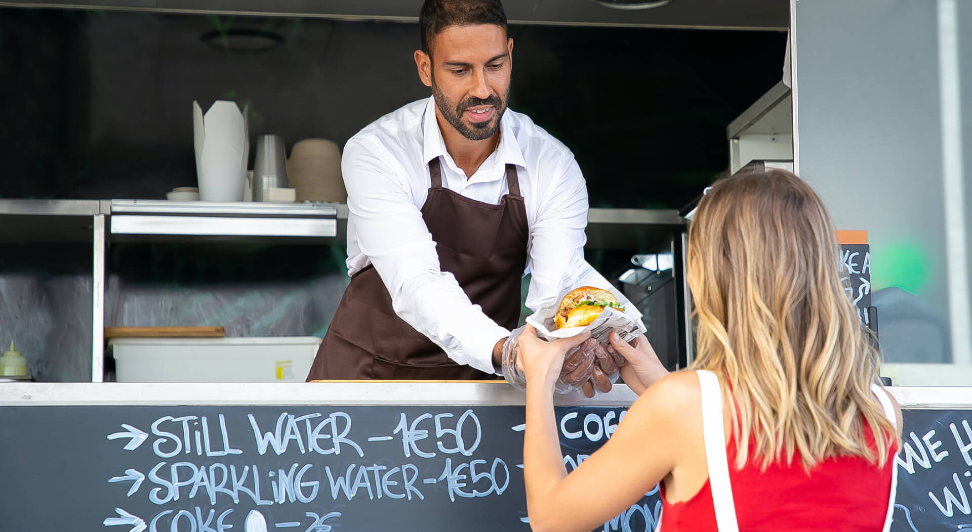 food truck owner serving a cheeseburger to a customer