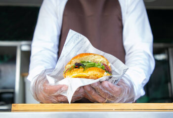 food truck server holding a medium sized hamburger