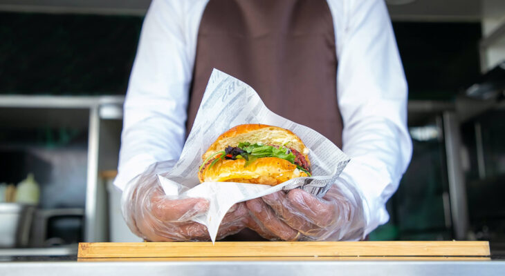 food truck server holding a medium sized hamburger