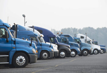 row of blue semi truck for sale at a parking lot