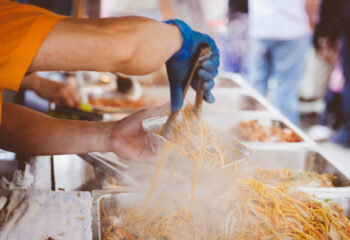 food truck server preparing noodles for a customer