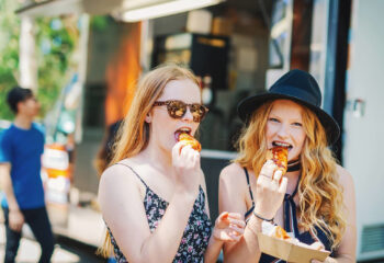 two girls enjoying their food at a food truck festival